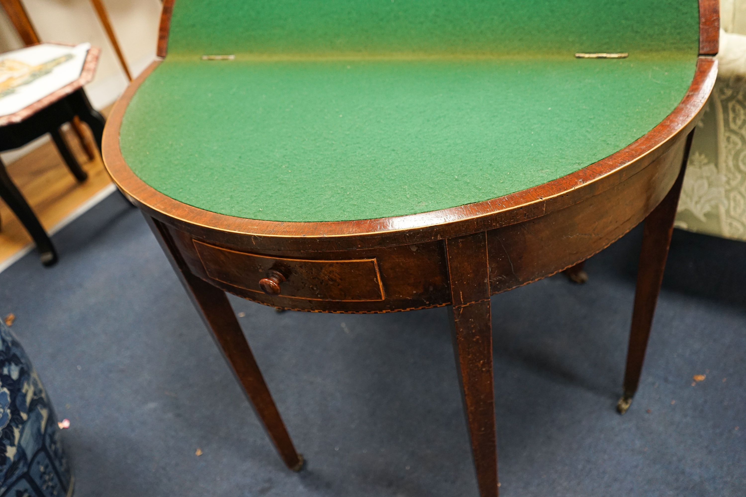 A Georgian mahogany demi-lune card table, with folding top on square tapered legs, width 86cm, depth 41cm, height 71cm